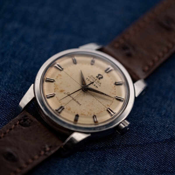 Low crown-side view of the Omega Seamaster showing the domed crystal, crosshair dial and crown