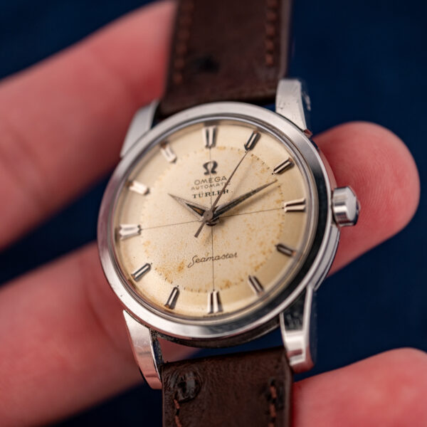 Hand-held angled view of the vintage Omega Seamaster showing its dial, crown and lower lugs
