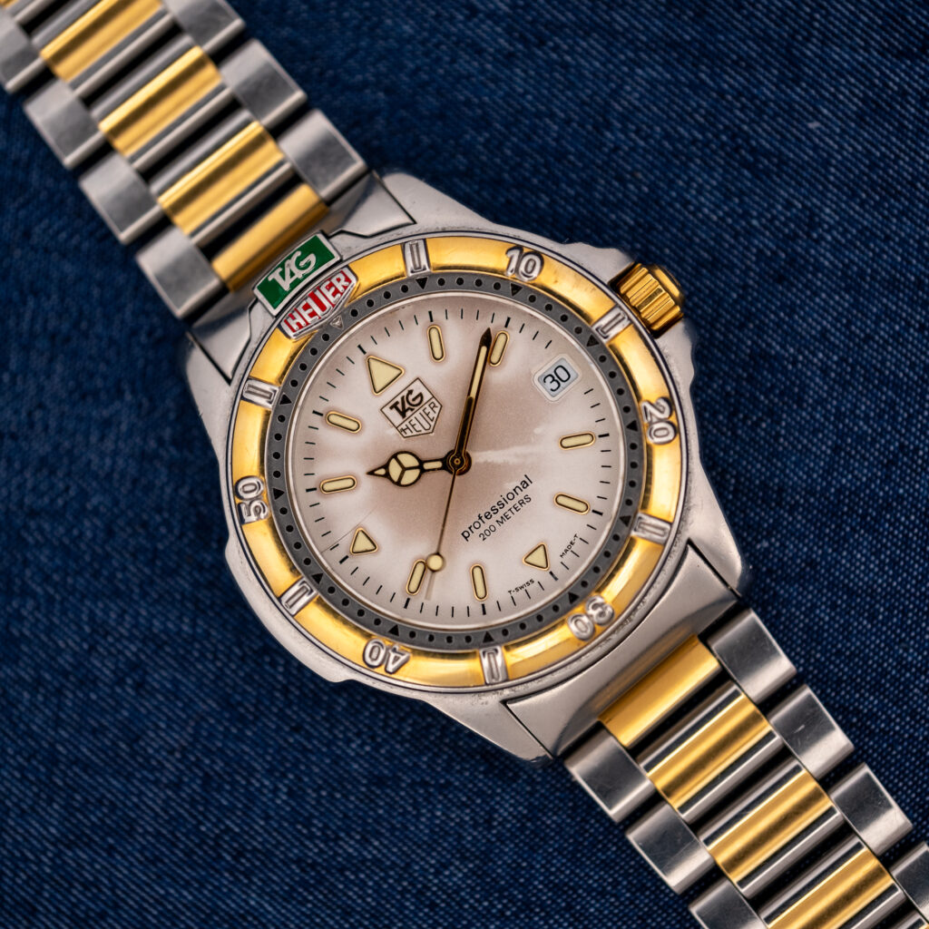 TAG Heuer 4000 Series 995.706 K at an angle, with cream dial, date window, gold-tone bezel and two-tone bracelet