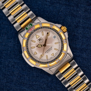 TAG Heuer 4000 Series 995.706 K at an angle, with cream dial, date window, gold-tone bezel and two-tone bracelet