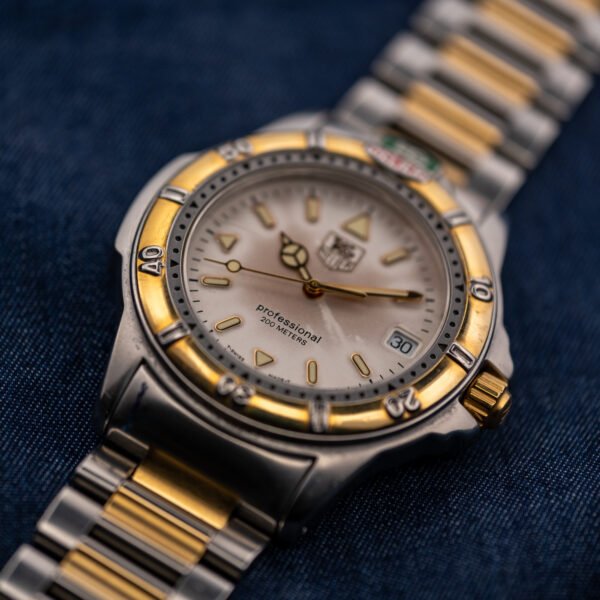 Low crown-side view of the TAG Heuer 995.706 K showing the cream dial and two-tone bracelet links