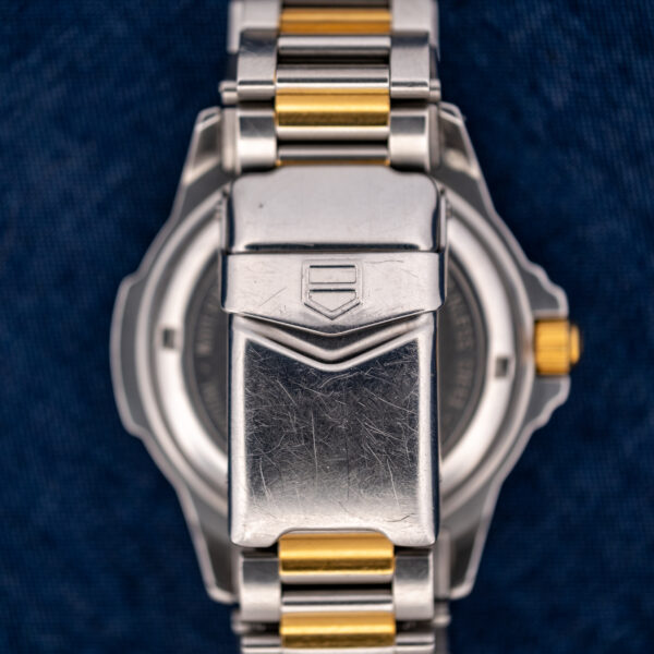 Closed folding clasp of the TAG Heuer 995.706 K, with outlined shield emblem and surface scratches