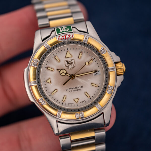 TAG Heuer 4000 Series 995.706 K held in hand, cream dial and gold-tone timing bezel facing forward