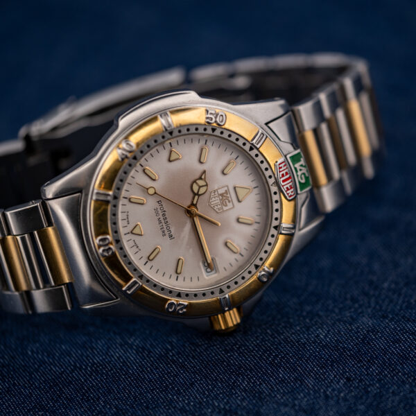Three-quarter view of the TAG Heuer 995.706 K with the bracelet open, cream dial and two-tone links