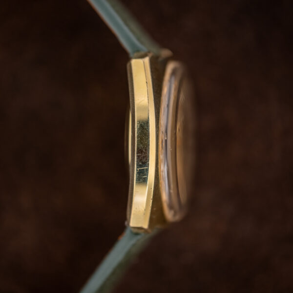 Opposite flank of the Omega De Ville cushion case in profile with the raised crystal above