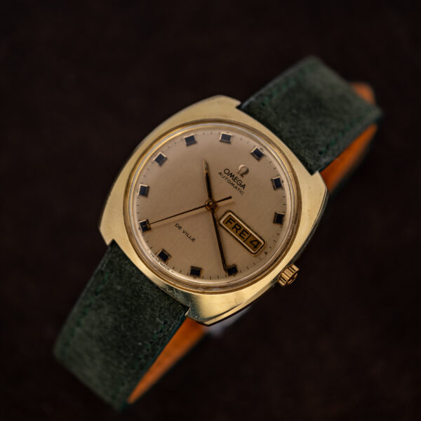 Omega De Ville day-date on a display stand with square hour markers and forest green strap