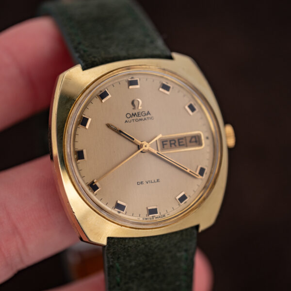 Hand-held angled view of the Omega 166.053 De Ville dial, day-date window and gold-tone cushion case