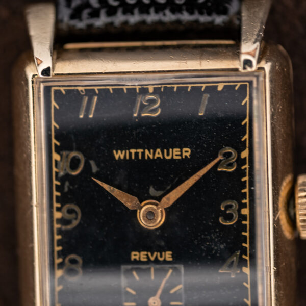 Upper half of the Wittnauer Revue black dial, signature and gold-toned numerals inside the rectangular minute border
