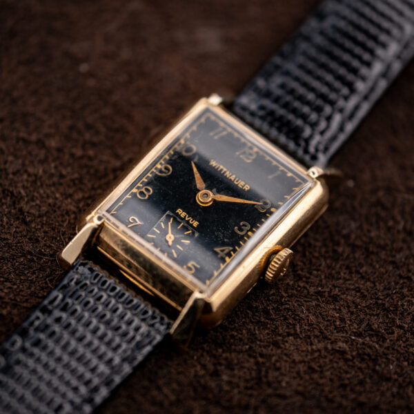 Low crown-side angle of the Wittnauer Revue, black dial and gold-toned hands framed by the rectangular case