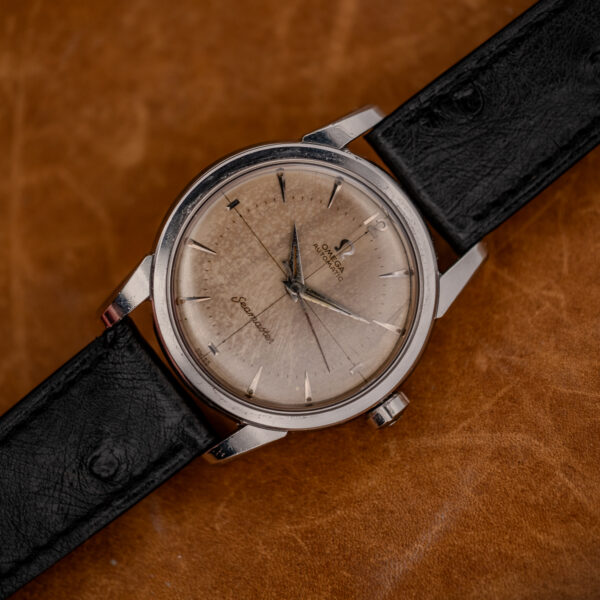 Diagonal front view of the Omega Seamaster crosshair dial on a stitched black ostrich strap