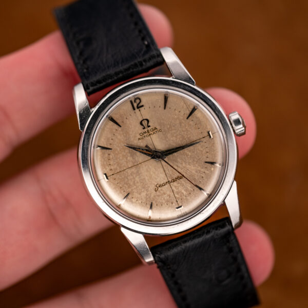 Close hand-held view of the Omega Seamaster showing Arabic twelve, crosshair lines and marbled dial