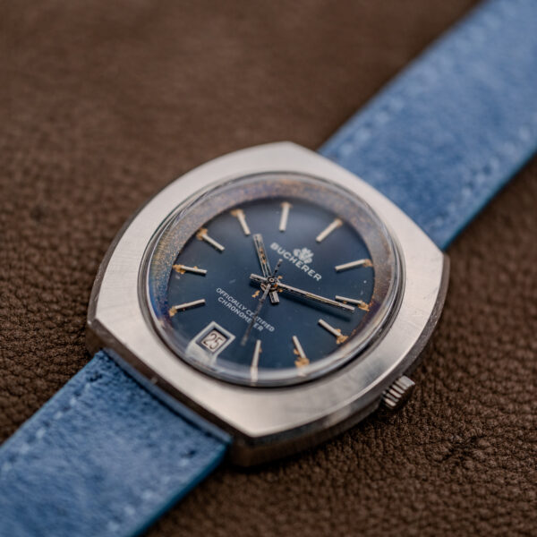 Low crown-side view of the Bucherer chronometer with blue dial, date at six and ridged crown