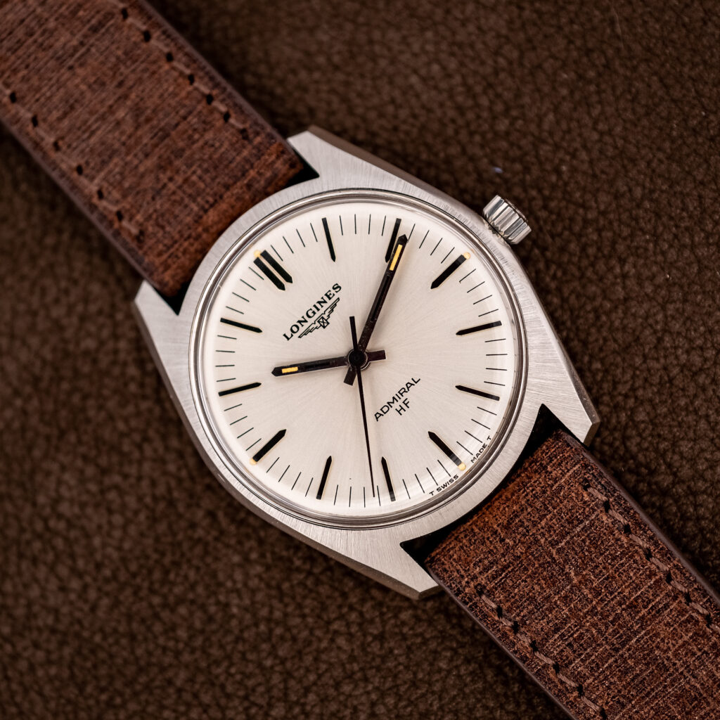 Longines Admiral HF 2301-4 at an angle: white radial dial, pointed baton hands, angular brushed steel case, brown strap