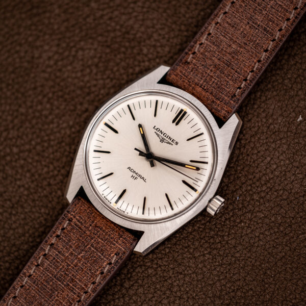 Wide angled view of the Longines Admiral HF manual-wind watch, its cushion-like steel case and brown strap in frame
