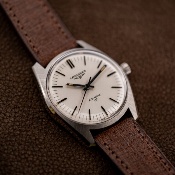 Longines Admiral HF from the side opposite the crown, light dial and brushed steel case at a low angle
