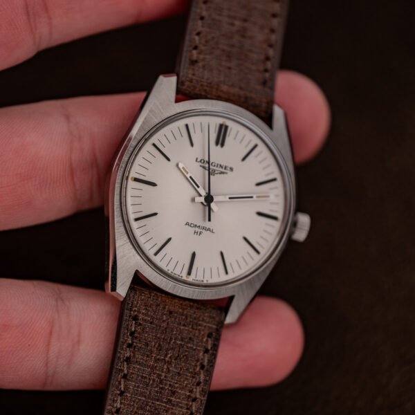 Longines Admiral HF held in hand at an angle, showing the cushion-like case and white radial-brushed dial