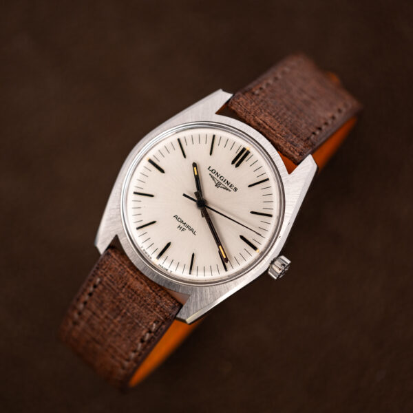 Longines Admiral HF tilted upward on its brown strap, white dial and angular steel case seen from above