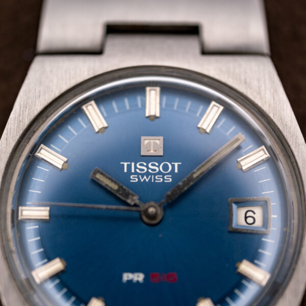 Upper dial of the Tissot PR 516 showing the applied T emblem, Tissot signature and date window at three