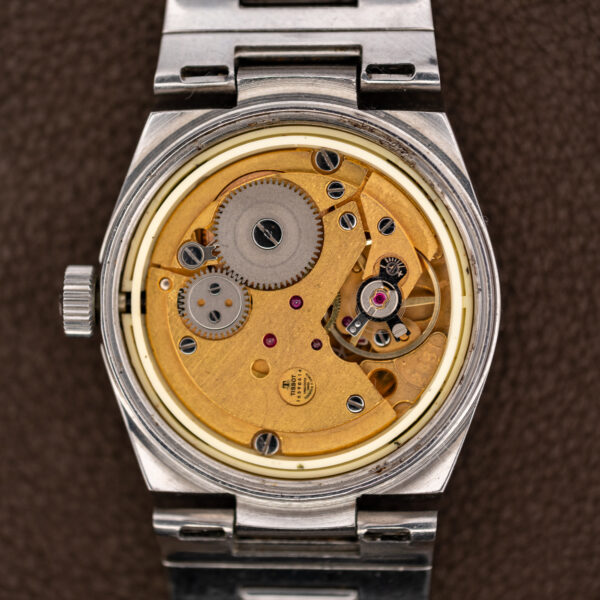 Open Tissot case showing the signed manual-wind movement seated inside its pale movement ring