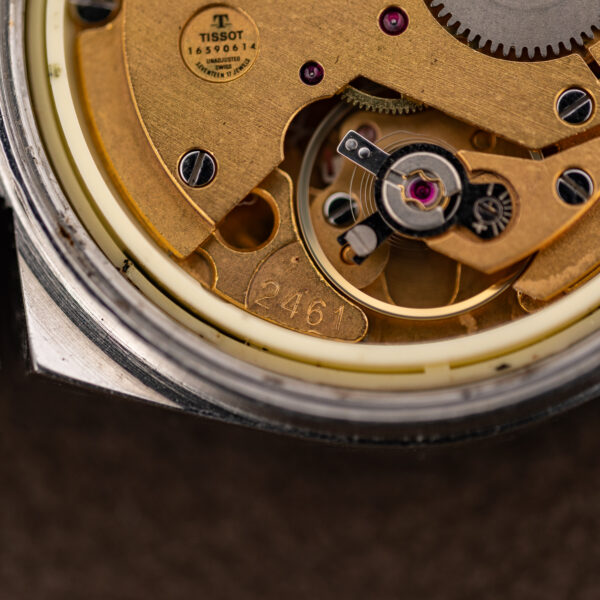 Macro of the Tissot caliber 2461 stamp beside the balance in the hand-wound movement