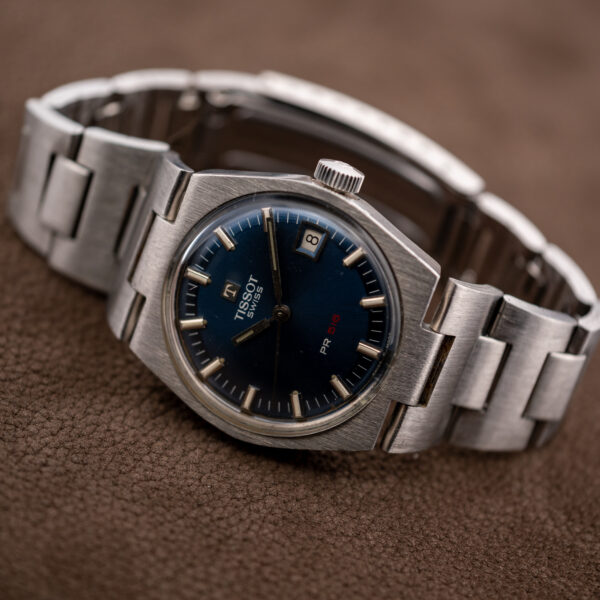 Tissot PR 516 on a stand from a low angle, with blue dial, date window and bracelet loop