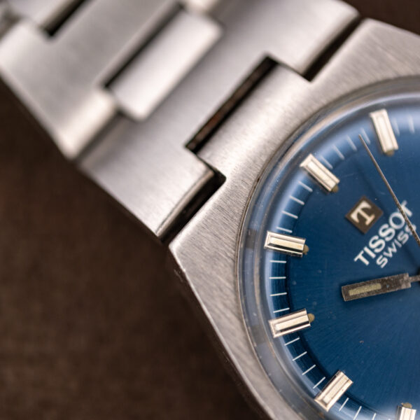 Tissot PR 516 upper case shoulder close-up with baton markers and broad bracelet links