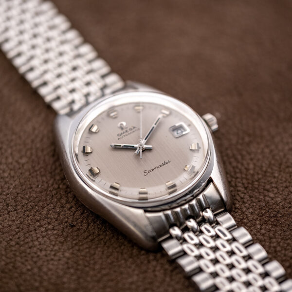 Low oblique view of the Omega Seamaster grained silver dial and the broad shoulders of the case