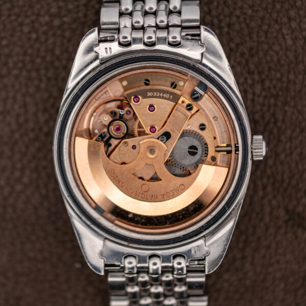 Open caseback of the Omega Seamaster 166.067 showing the caliber 565 automatic movement and bracelet end links