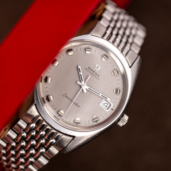 Angled front of the Omega Seamaster 166.067 showing the silver dial, framed date and bracelet end link