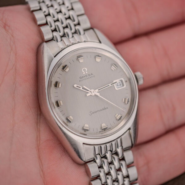 Omega Seamaster 166.067 held in hand, showing the silver date dial and multi-row steel bracelet