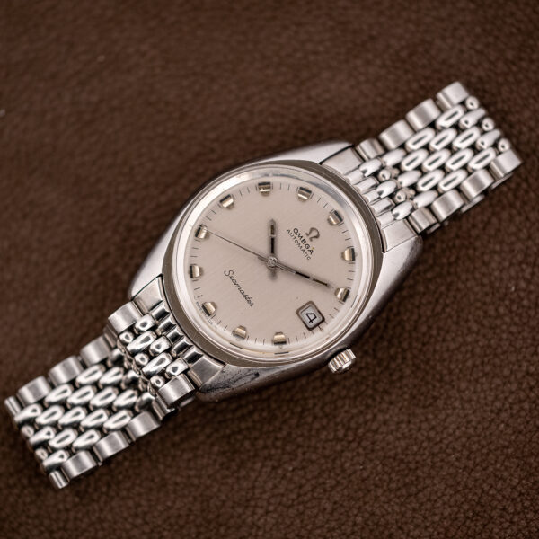 Full diagonal view of the Omega Seamaster 166.067 with silver date dial, tonneau case and steel bracelet