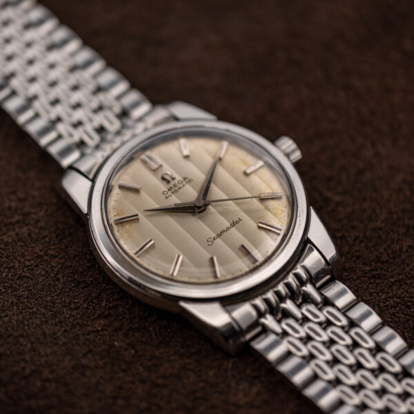 Low crown-side view of the Omega Seamaster showing alternating dial bands, crown and bracelet end links
