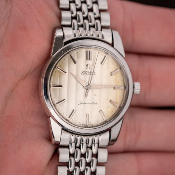 Hand-held front view of the Omega Seamaster 165.009 ribbon dial and silver bracelet