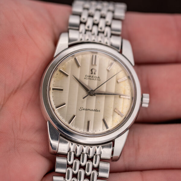Hand-held angled view of the Omega Seamaster ribbon dial showing vertical bands and baton markers
