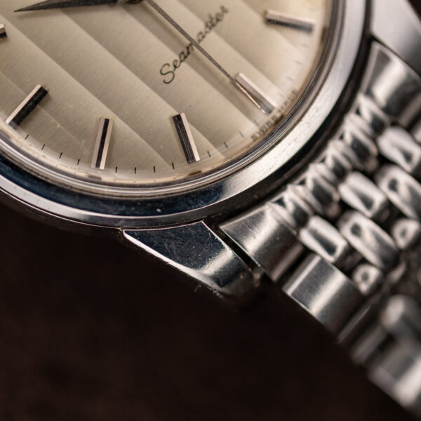 Close-up of the lower ribbon dial bands, scratched steel bezel and bracelet end link