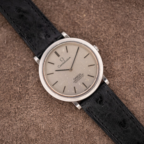 Front view of the steel Omega Constellation 157.0001 on a brown surface, with two hands and baton markers