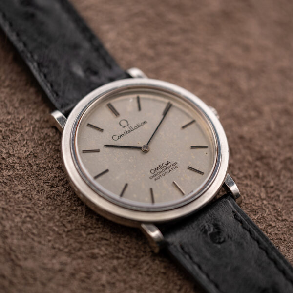 Omega Constellation cal. 712 from the left at a low angle, with speckled silver dial and black strap
