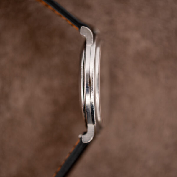 Opposite profile of the Omega 157.0001 case with downturned lugs, crystal edge and fine scratches on the flank