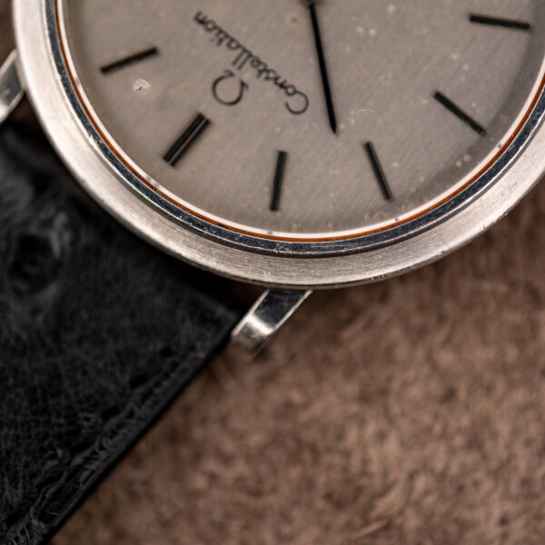 Macro of the Omega Constellation bezel and lug showing surface scratches beside the upper dial and Constellation script