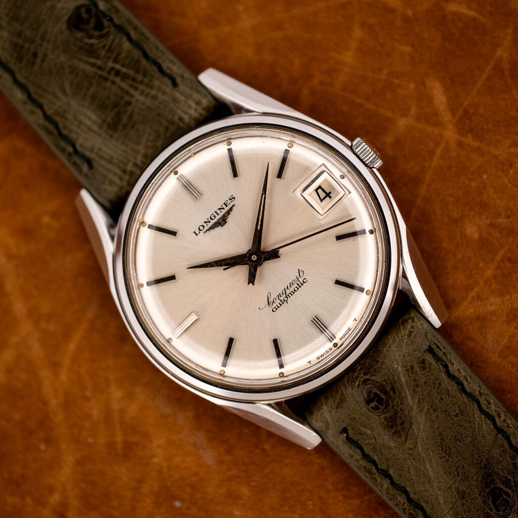 Longines Conquest 7171-2 seen diagonally, silver sunburst dial with applied batons, date at three and olive strap
