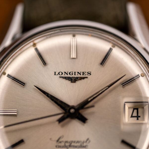 Upper dial macro of the Longines Conquest 7171-2 showing the winged-hourglass applique, ridged batons and date window