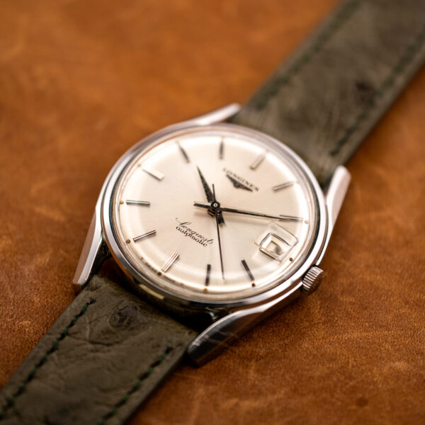 Low diagonal view of the Longines Conquest 7171-2 with its olive ostrich strap running out of frame