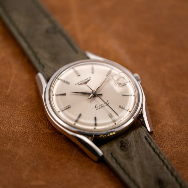Low oblique angle across the Longines Conquest 7171-2 dial, catching the sunburst finish and applied markers