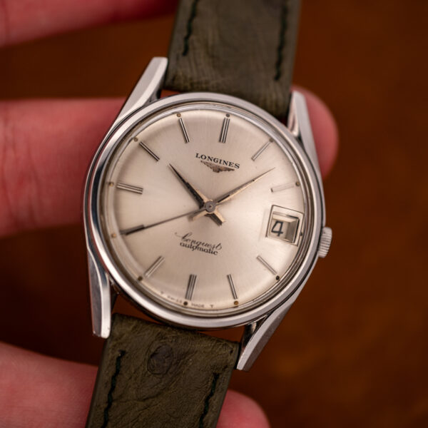 Longines Conquest 7171-2 held in hand, silver sunburst dial facing the camera