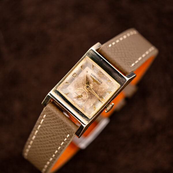 Longines Art Deco tank on a stand with its rectangular eggshell dial and taupe stitched strap