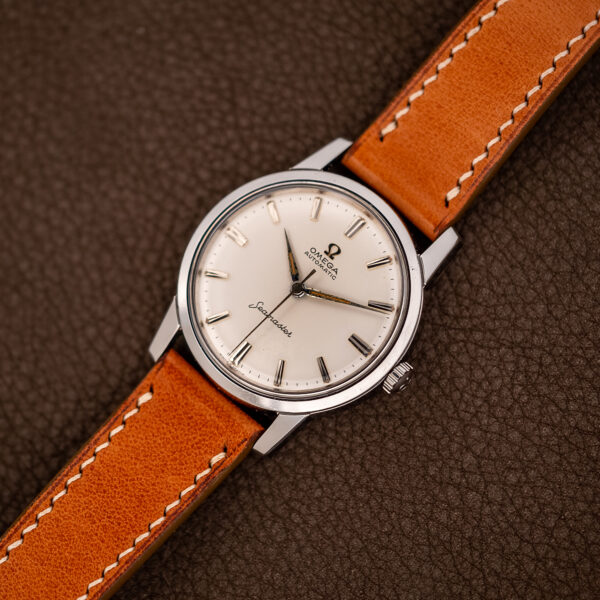 Diagonal front view of the Omega Seamaster 14704 white dial beside its tan contrast-stitched leather strap