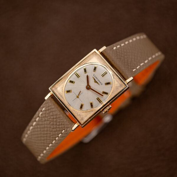 Longines 1137-370 on a display stand showing the rectangular case, oval dial and stitched taupe strap