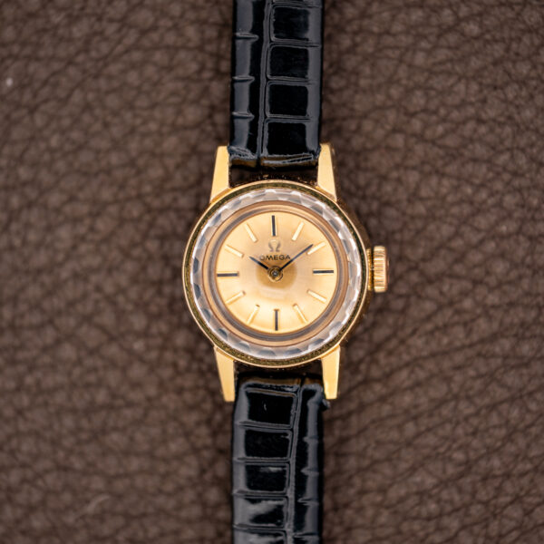 Straight-on view of the Omega 511.166 with faceted crystal, two-hand champagne dial and gold-tone case